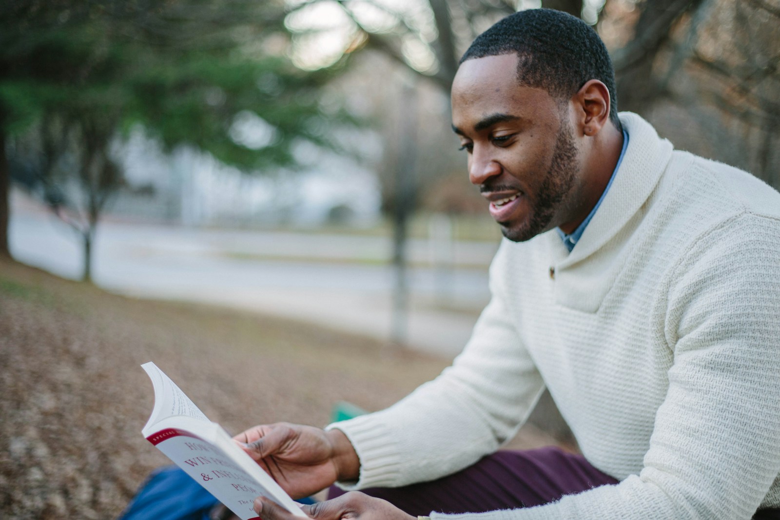 man wearing white sweater while reading book about common auto coverages
